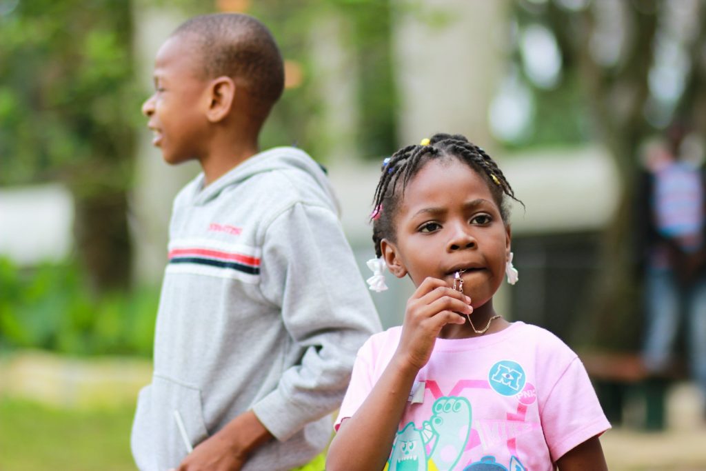 selective focus photography of girl biting her pendant beside a boy in gray pullover hoodie