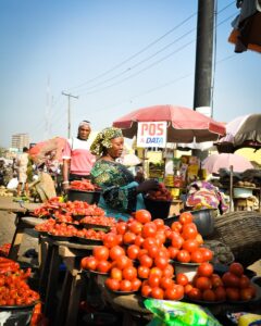 A group of people standing around a table filled with tomatoes/Wills